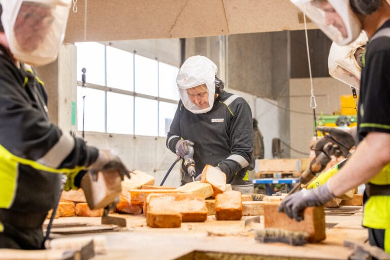 Arbejdere renser mursten i fabrik.