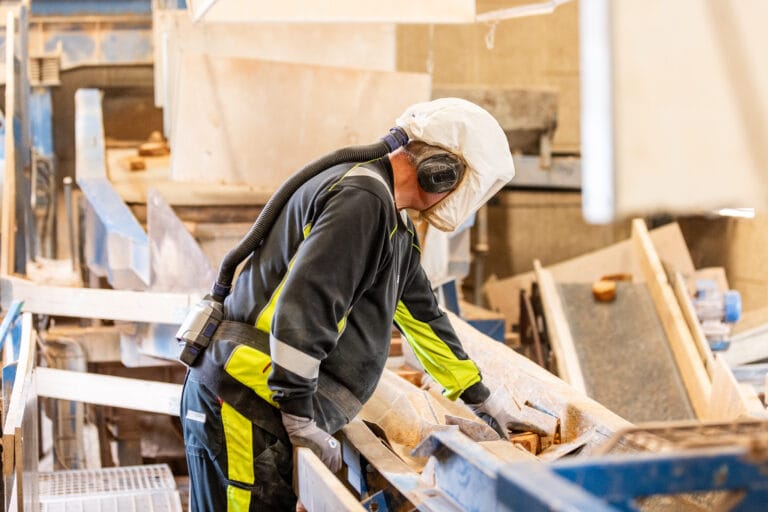 Arbejder med beskyttelsesudstyr betjener maskine på fabrik