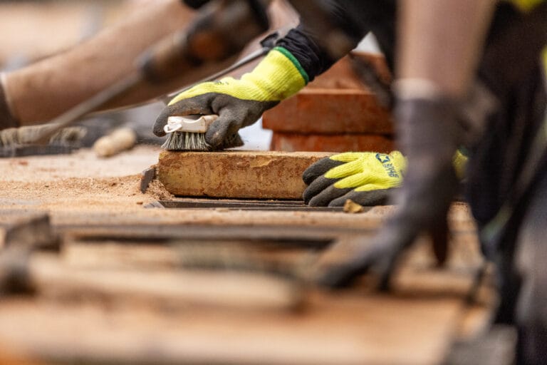 Person rengør mursten med børste på byggeplads
