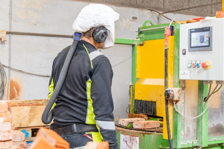 Arbejder betjener maskine til behandling af mursten